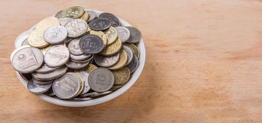 Malaysian coins in a white bowl over wooden surface