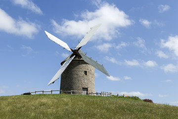 Fototapeta na wymiar A wind mill in France on a hill with blue sky