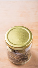 Malaysian coins in a mason jar over wooden background
