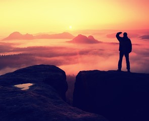 Fototapeta na wymiar Hiker stand on peak of empires, red foggy day