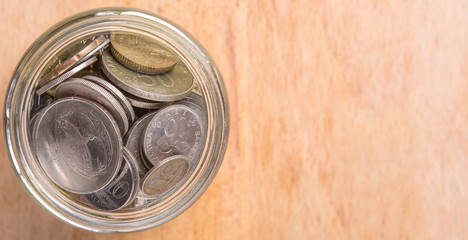 Malaysian coins in a mason jar over wooden background