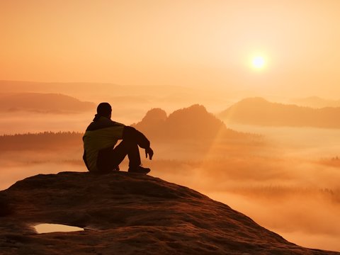 Spring landscape. Hiker in black on the rocky peak. 