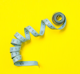 twisted tape measure on yellow background