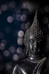Black Buddha statue with bokeh screen background.