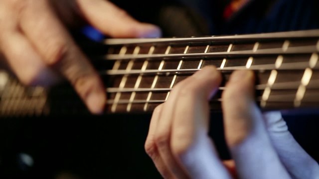 Musician playing bass guitar; extreme closeup, 