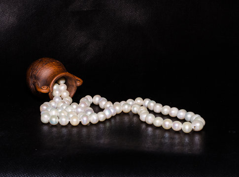 Ancient amphora and pearls over black