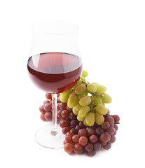 Glass of red wine next to a branch of grapes