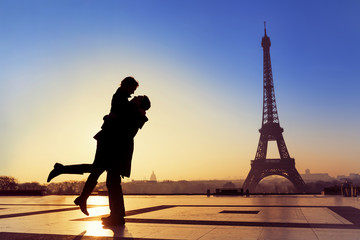 Young couple in love at Eiffel Tower - obrazy, fototapety, plakaty