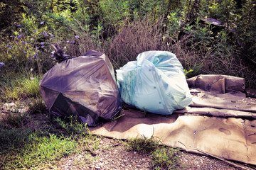 Illegal dumping in the nature - garbage bags left in nature - toned image