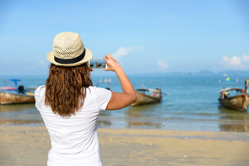 Tourist on thai beach at Krabi taking photo with smartphone
