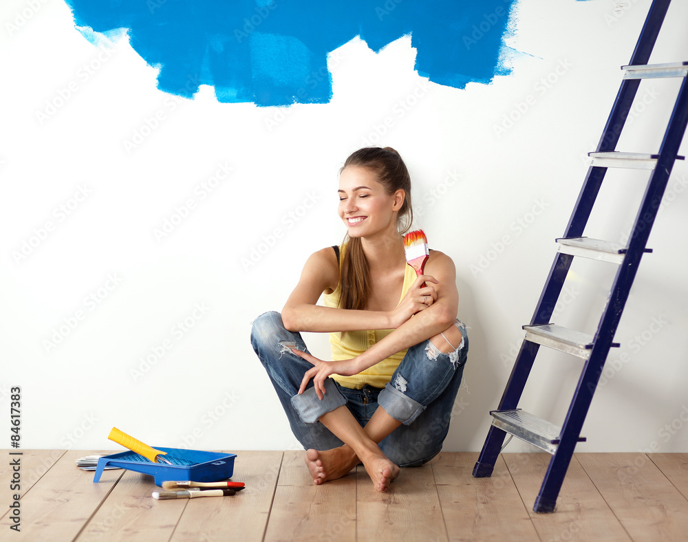 Wall mural Portrait of female painter sitting on floor near wall after