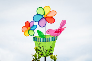 Colorful double pinwheel with bird on white sky