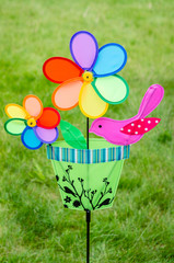 Colorful double pinwheel with bird on green grass