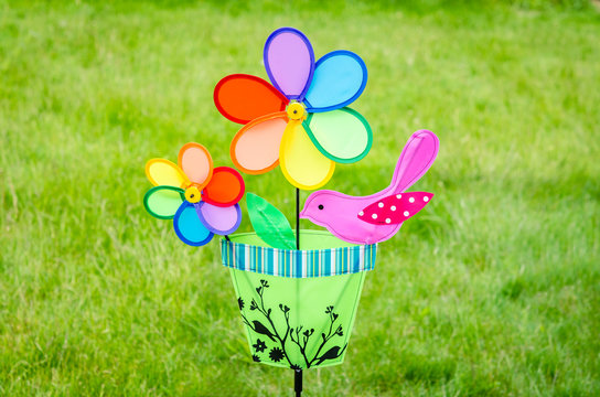 Colorful double pinwheel with bird on green grass
