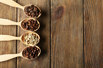 Coffee beans in spoons on wooden background