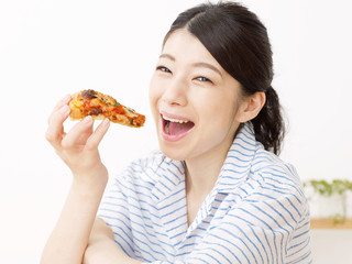 部屋でピザを食べる女性