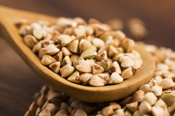 Buckwheat with a spoon on a wooden boards background