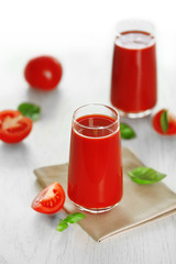 Tomato juice and fresh tomatoes on wooden table close-up