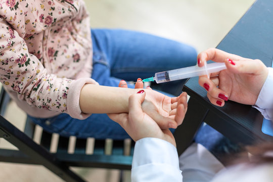 Woman a doctor making vaccination a child's hand, close up view