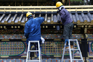 Restoration workers are painting a roof at a buddhist temple in