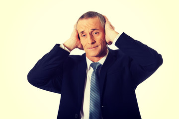 Portrait of tired man covering ears with hands