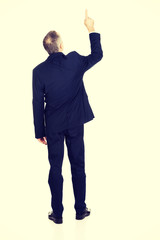Full length businessman pointing upwards