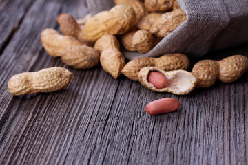peanuts in a miniature burlap bag on wooden surface