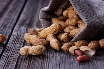 peanuts in a miniature burlap bag on wooden surface