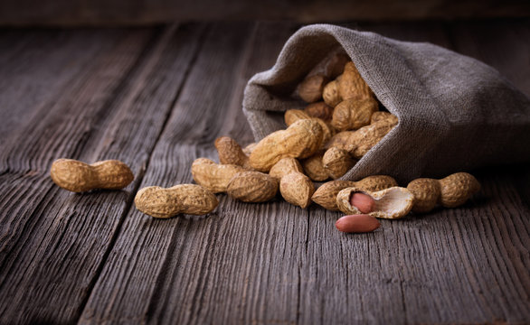 peanuts in a miniature burlap bag on wooden surface