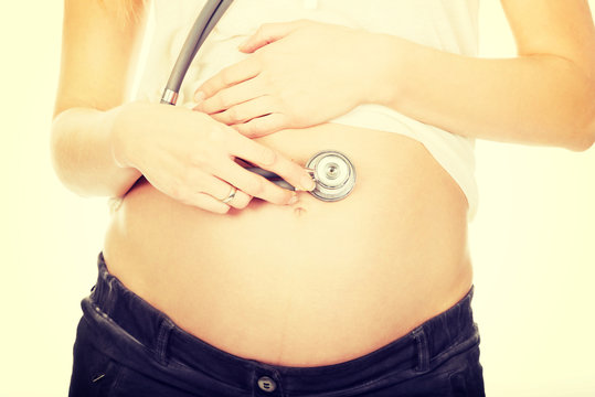 Pregnant woman with stethoscope listening her baby