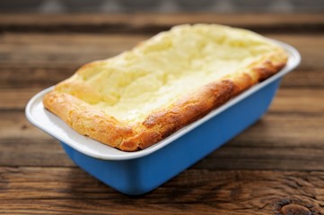 Homemade cottage cheese pie in blue baking pan on wooden backgro