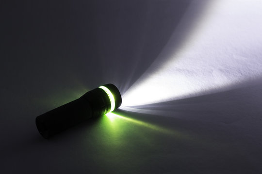 black flashlight lighting up shines green and white ray light beam torch. object emergency electric tool energy lamp lantern led battery power for security search or direction view finding in dark.
