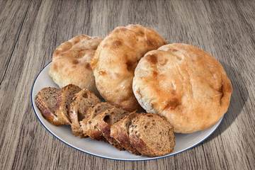 Plate with Pita Bread loafs and Baguette slices, on old Wood.