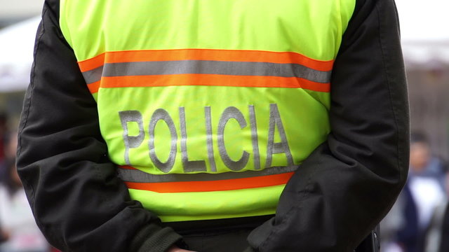 Anonymous police officers from the back wearing yellow fluorescent vests marked with the word police in the Spanish language.