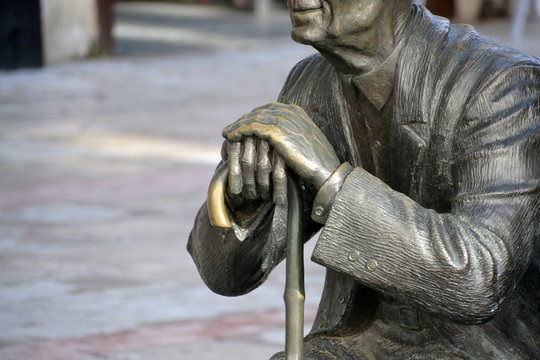 estatua de un hombre mayor sujetando un baston