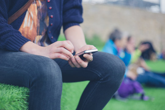 Woman sitting on astro turf using smart phone