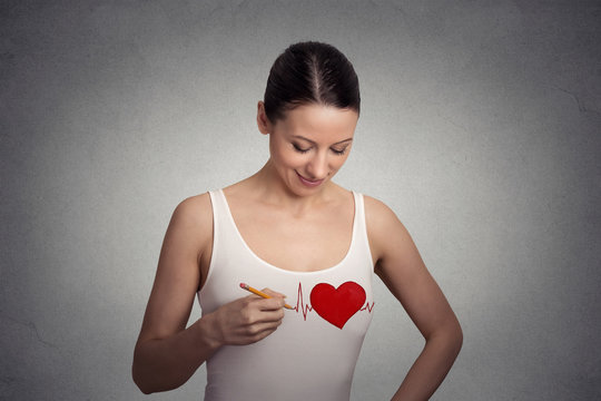 Heart beat. Young woman drawing a heart on her t-shirt