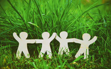 Wooden little men holding hands in summer grass. Symbol of frien