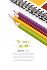 School supplies. Multicolored notebook and crayons on white background.