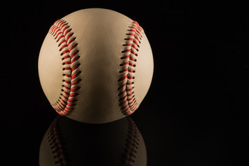 Close up of a baseball ball on black background with reflection