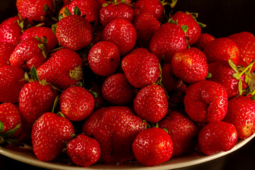 Close up of juicy garden strawberries on a white plate