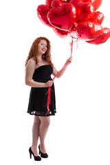 Close up view of a happy young girl with many red balloons.