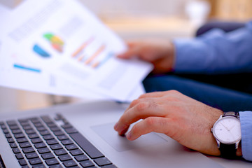 Businessman sitting at table with laptop and documents