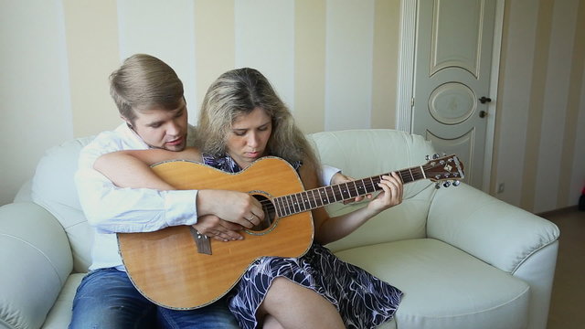 happy couple of musicians with guitar teach