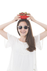 Mädchen mit sonnenbrille präsentiert auf ihrem kopf eine schale mit frischen erdbeeren