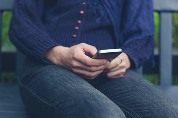 Woman sitting on bench using smart phone