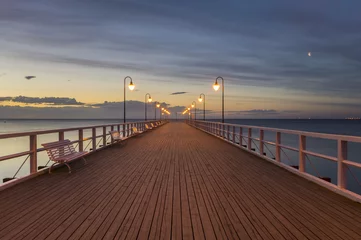 Gartenposter Seebrücke Holzsteg am Meer, nachts von stilvollen Lampen beleuchtet