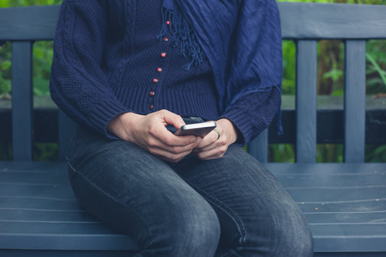 Woman sitting on bench using smart phone
