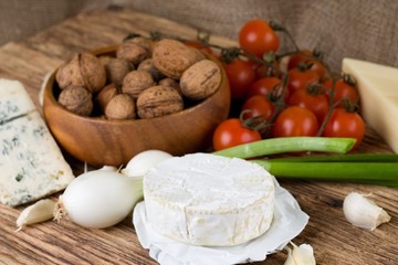 Whole camembert cheese on board with vegetable