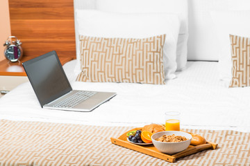 computer and a tray of food on the bed in the bedroom